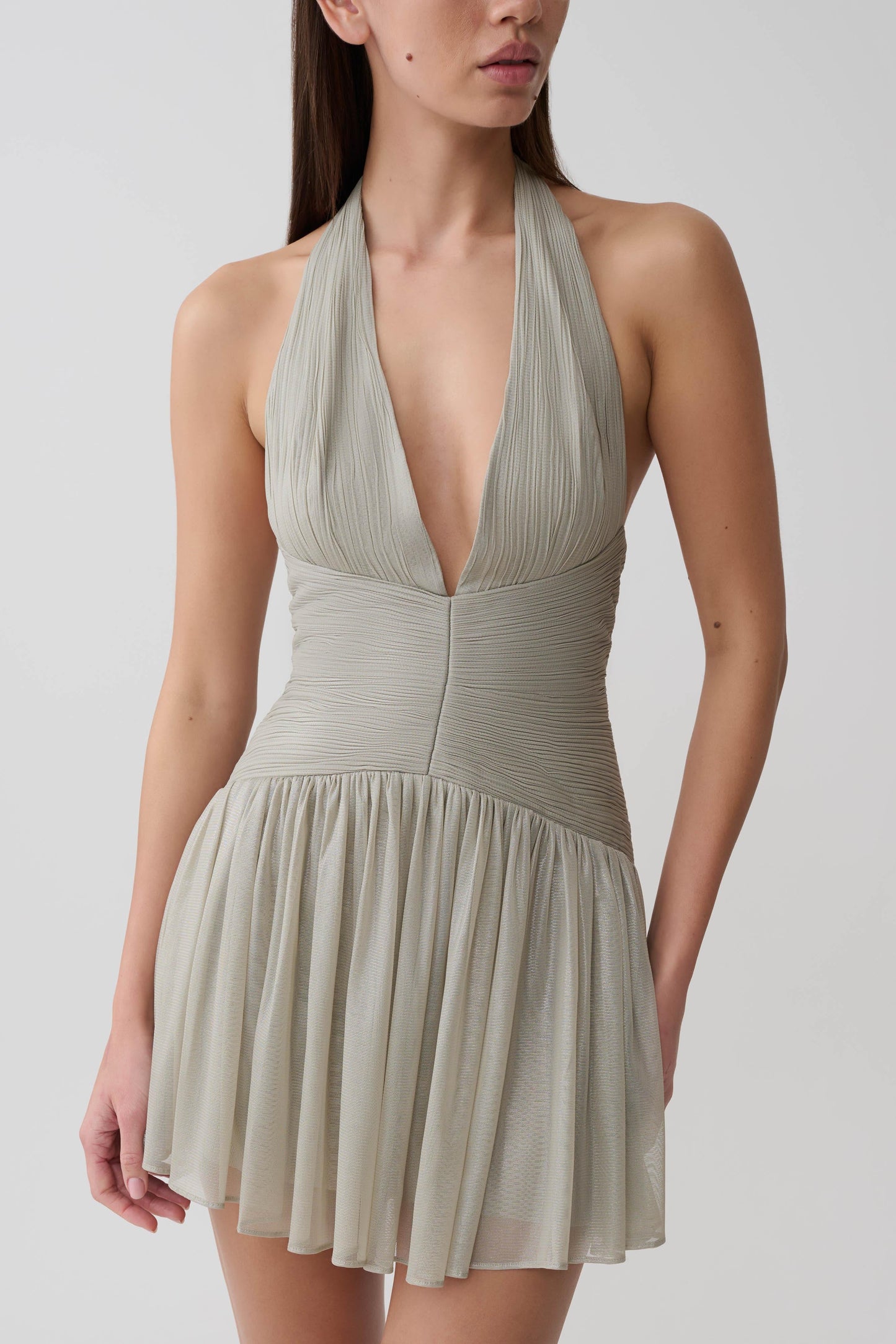 Womn wearing a silver halter pleated mini dress.