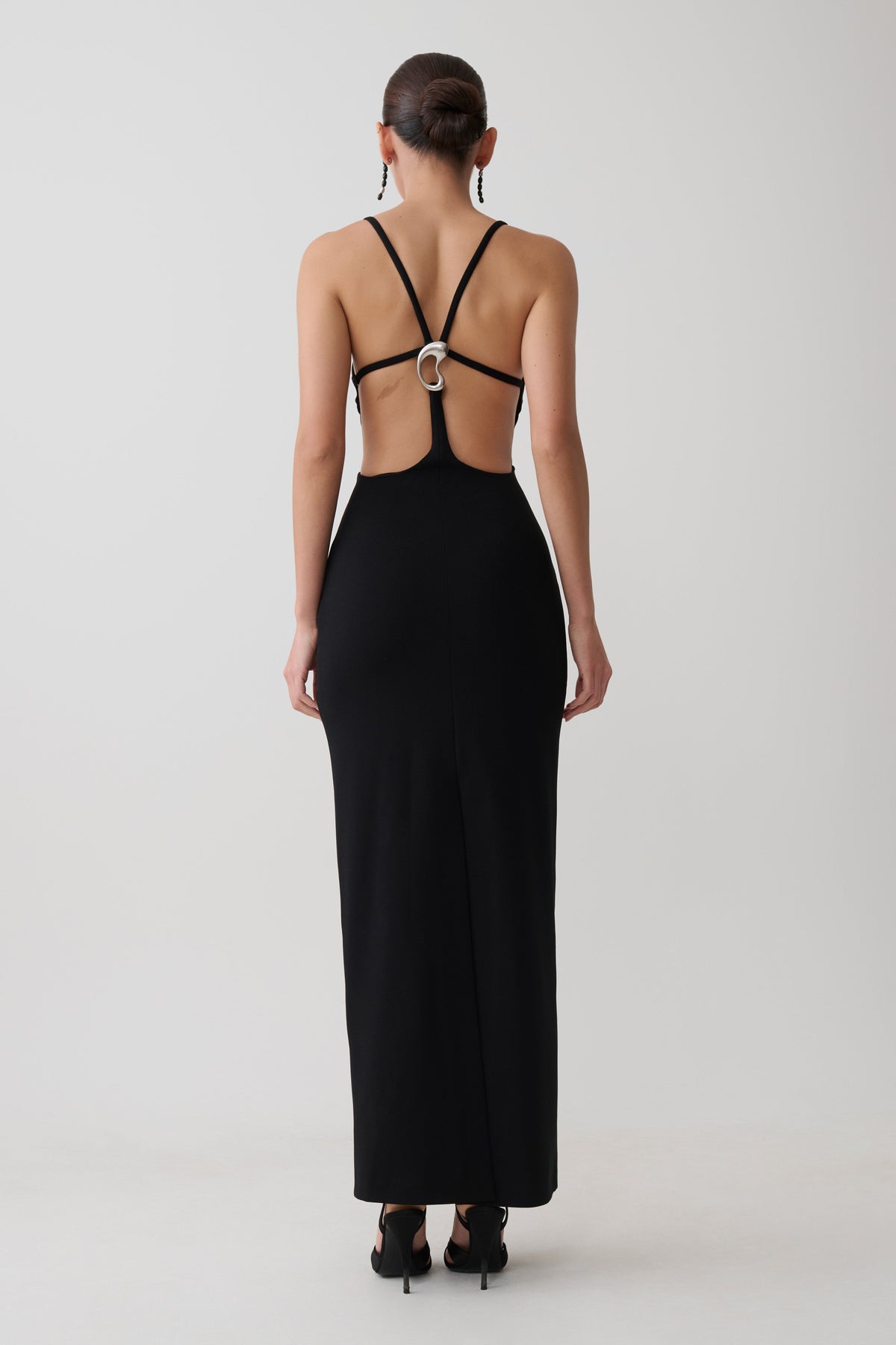 Woman wearing a crepe strapped back maxi dress with silver hardware.