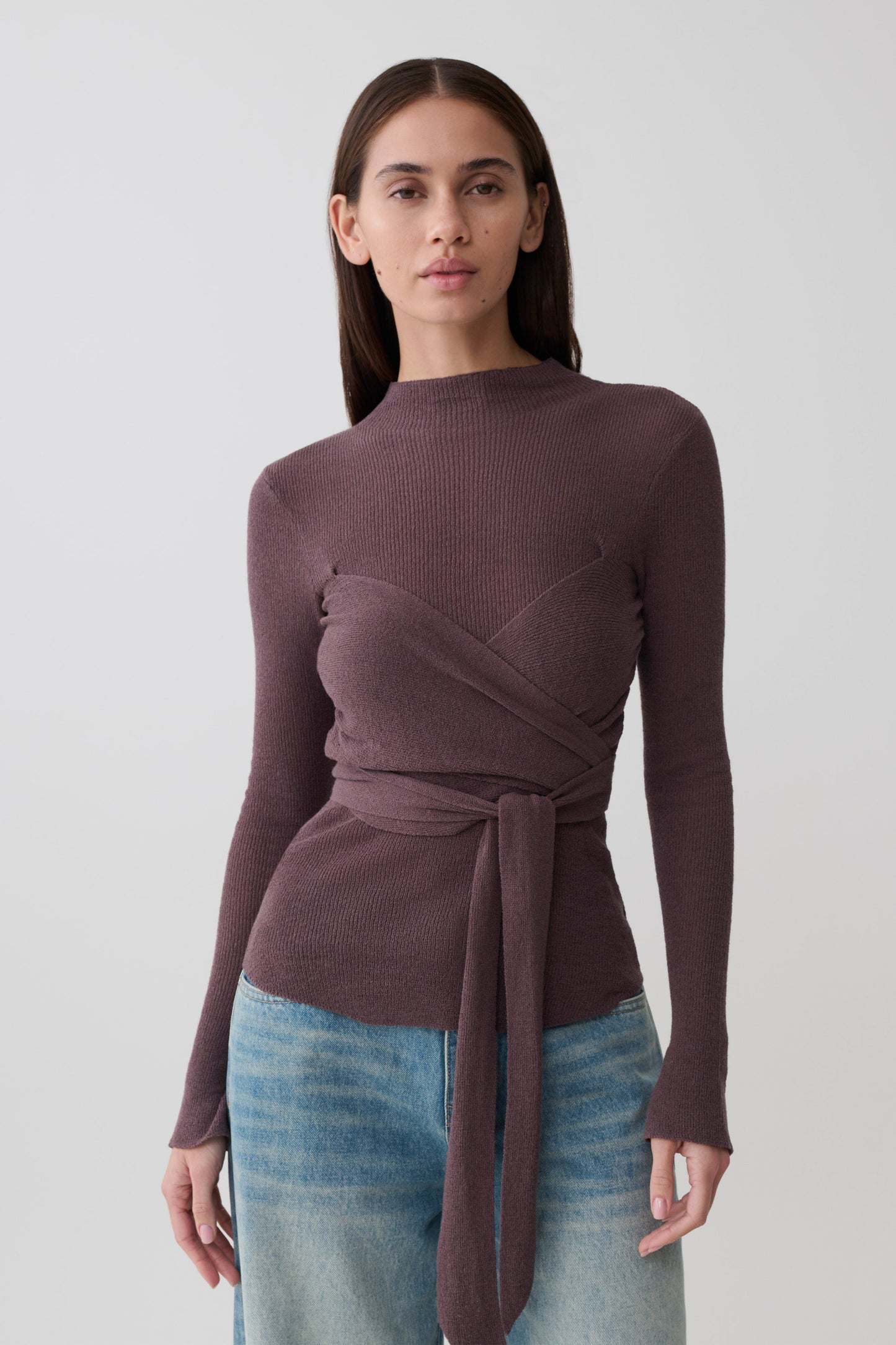 Woman wearing a brown wrap knit long sleeve top.