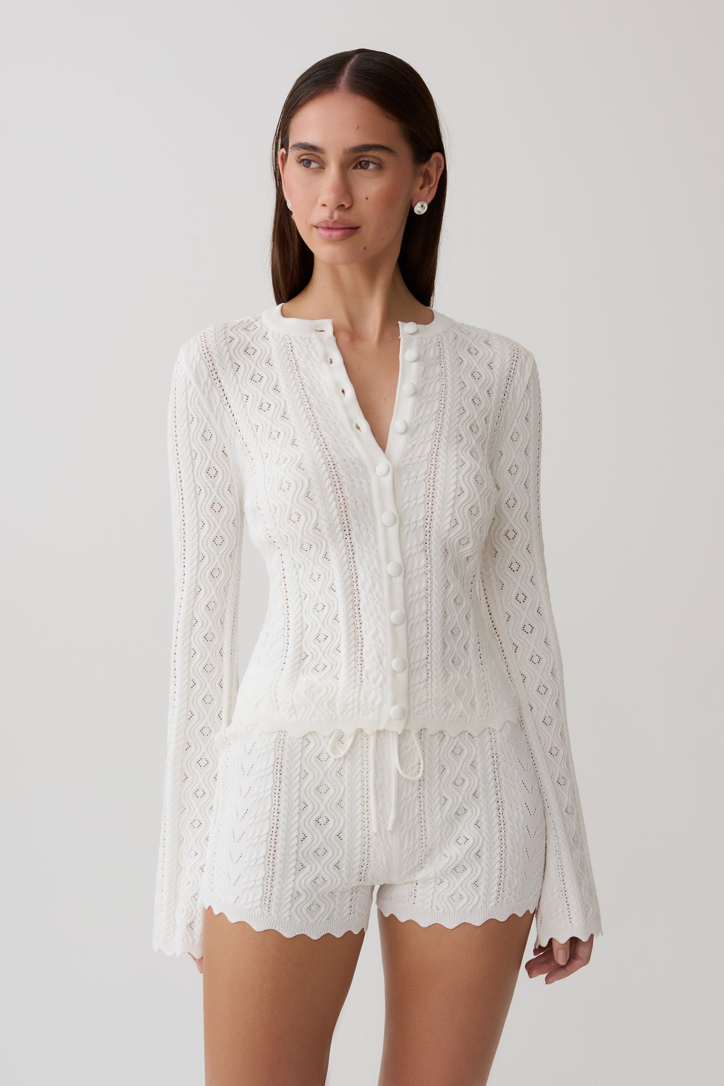 Woman wearing a white pointelle knit long sleeve top with matching shorts.