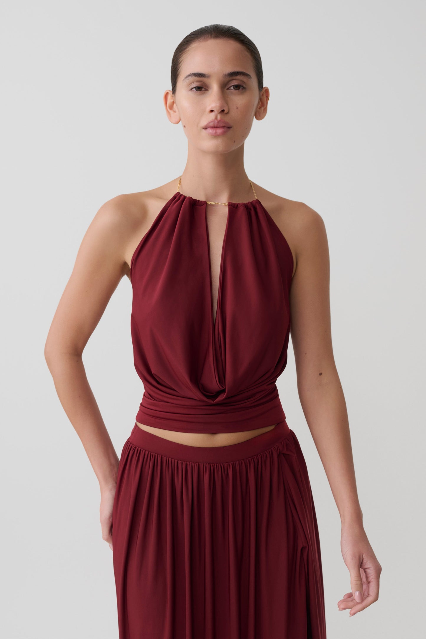 Woman wearing a dark red halter neck top with hardware.