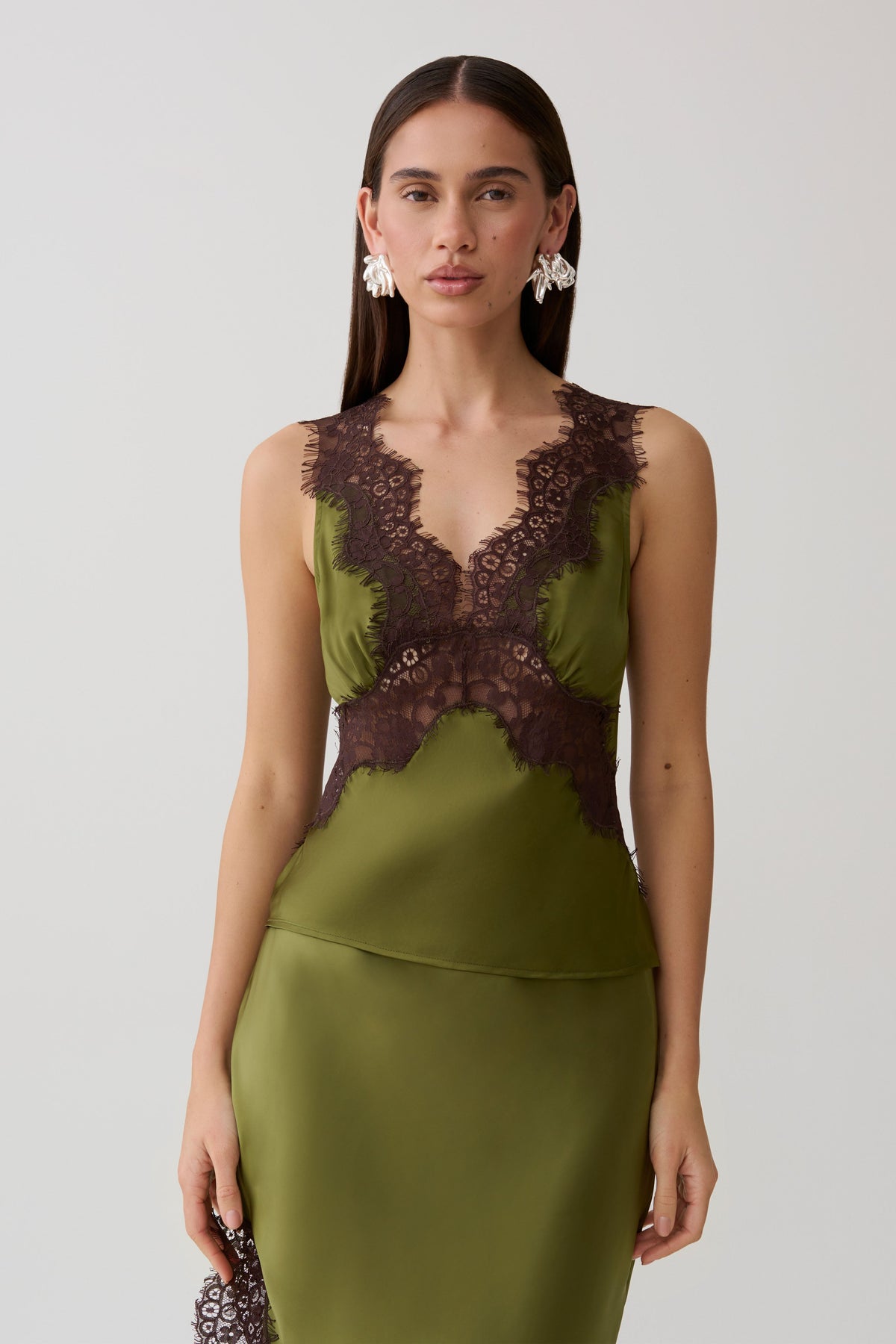 Woman wearing a green and brown satin and lace camisole.