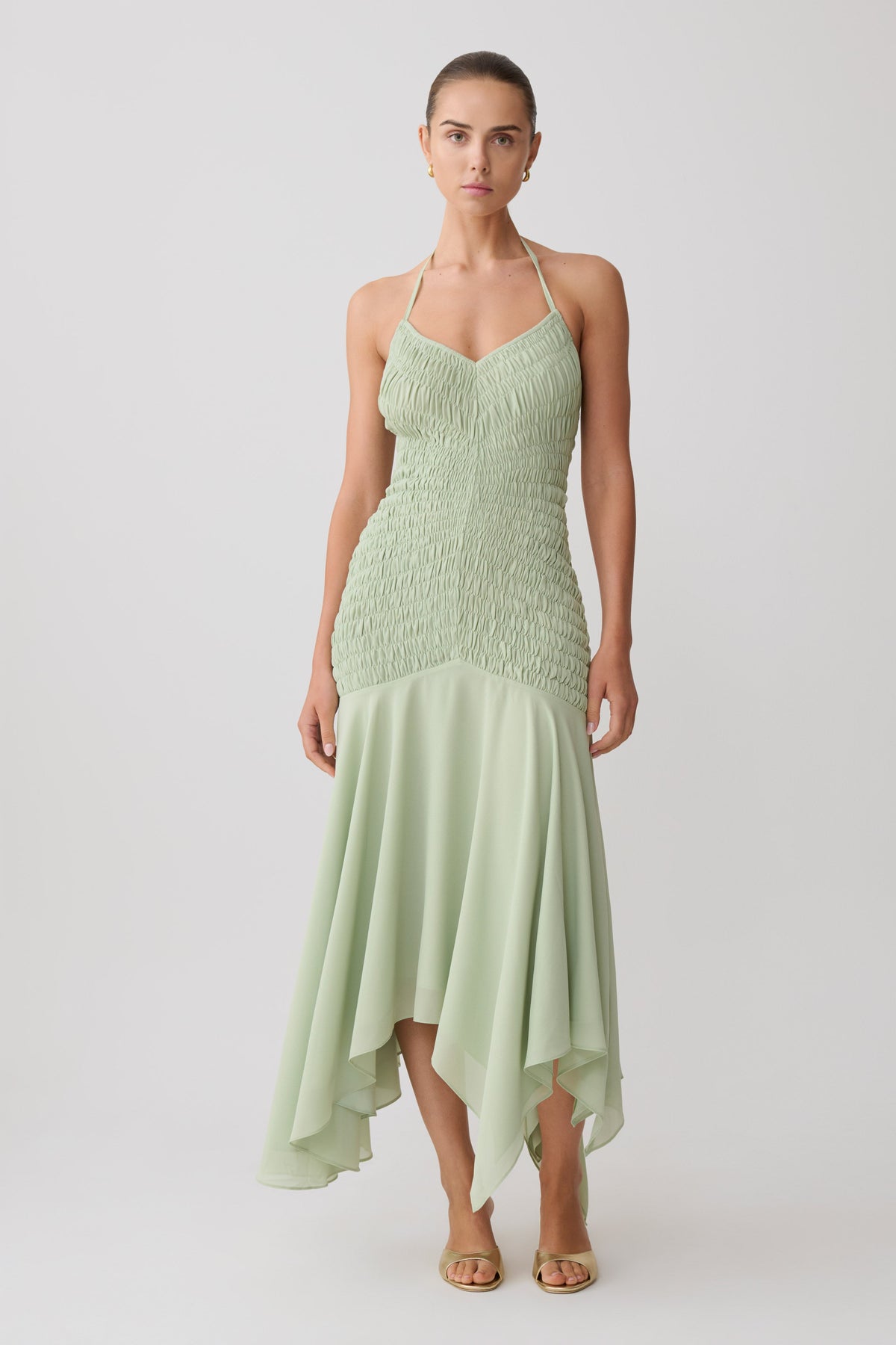 Woman wearing a light green shirred chiffon maxi dress.