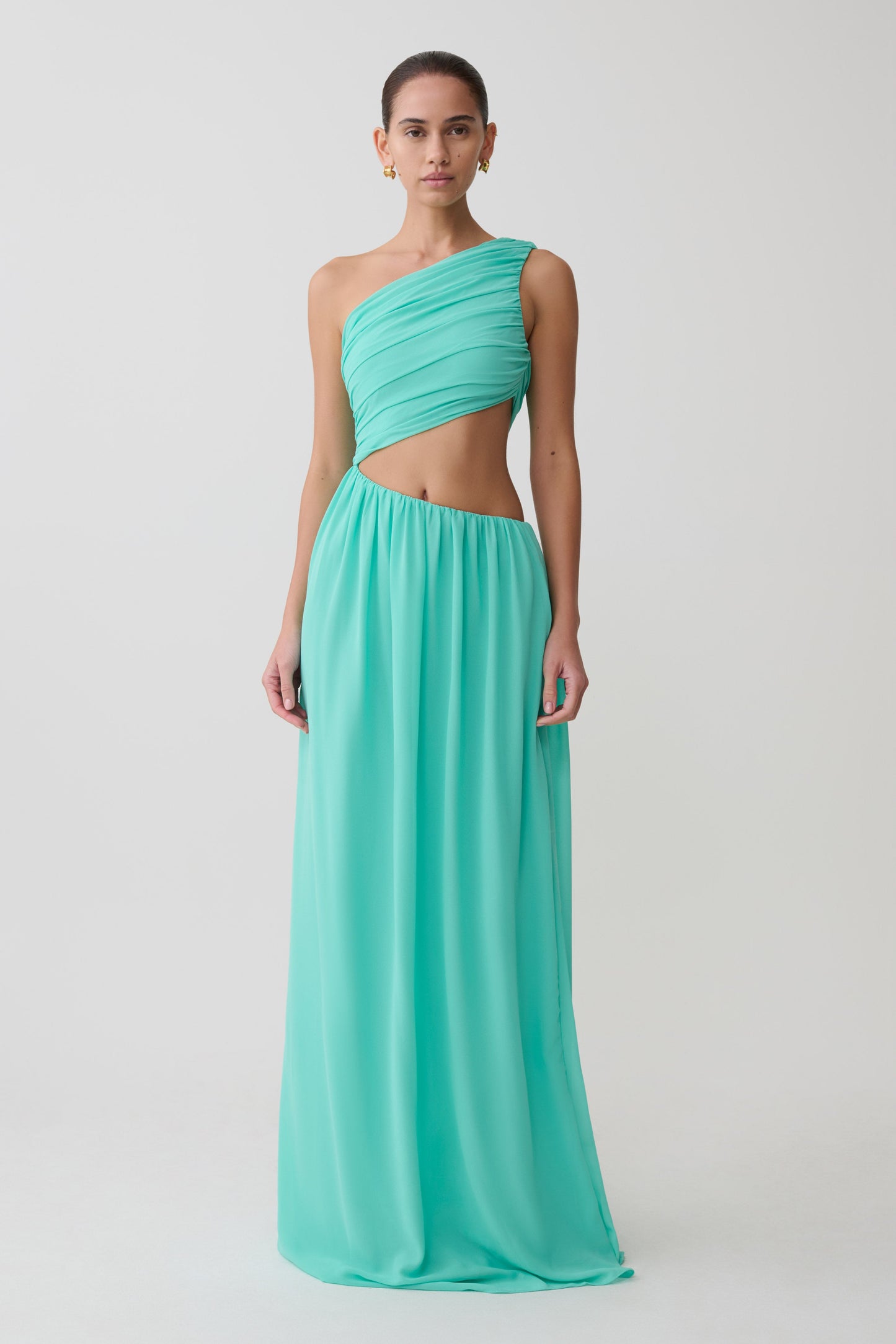 Woman wearing a turquoise one-shoulder evening gown on a white background
