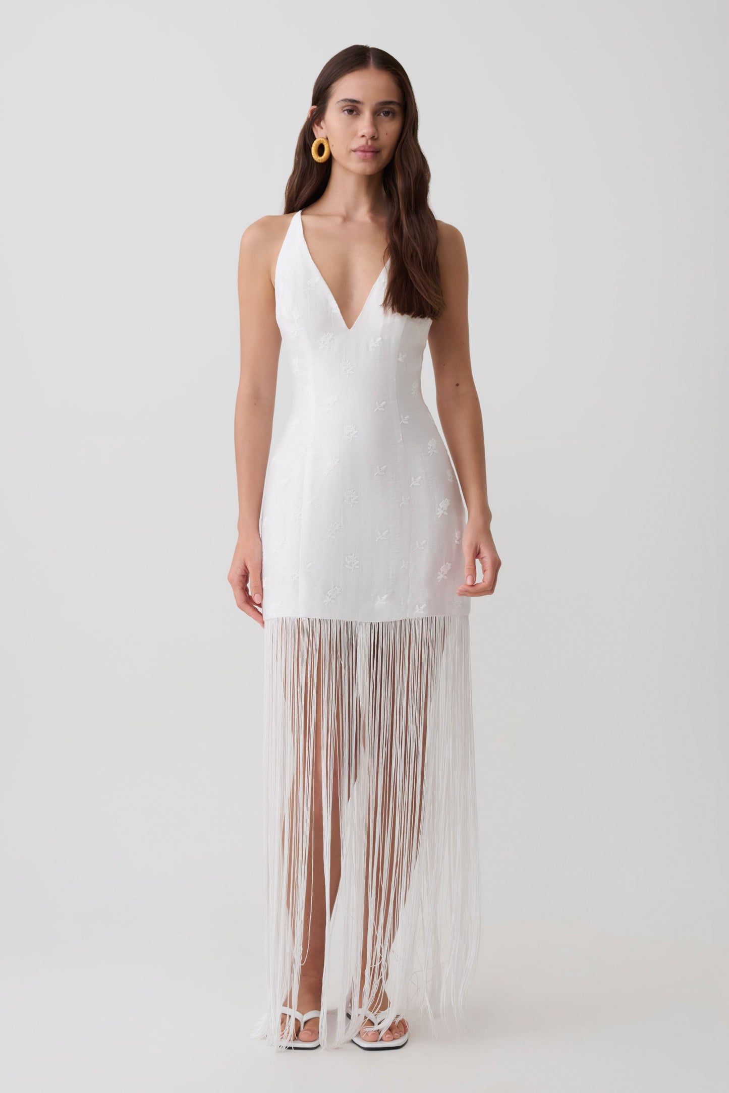 Woman wearing a v neck white fringe maxi dress.