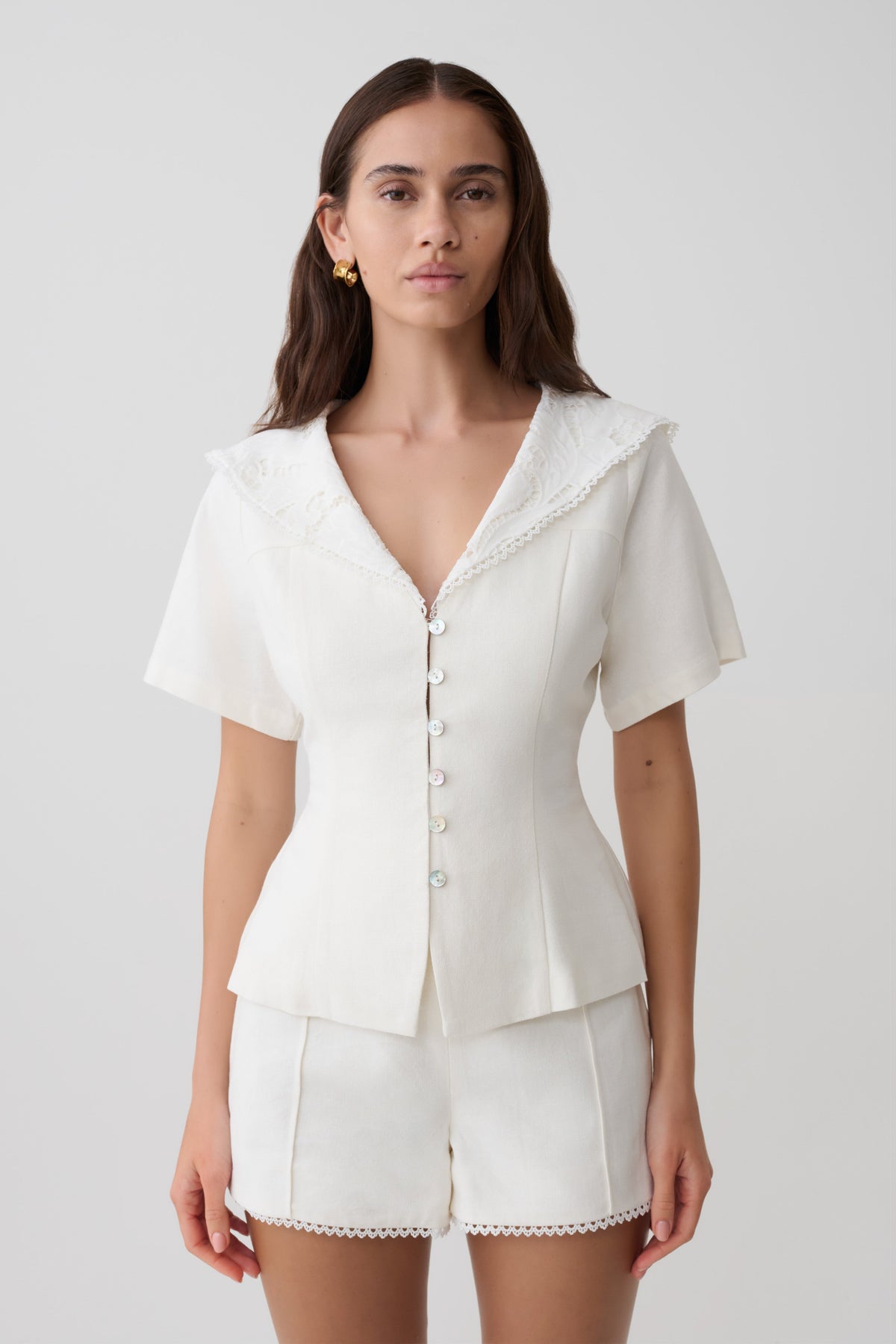 Woman wearing a white shortsleeve top with lace details.