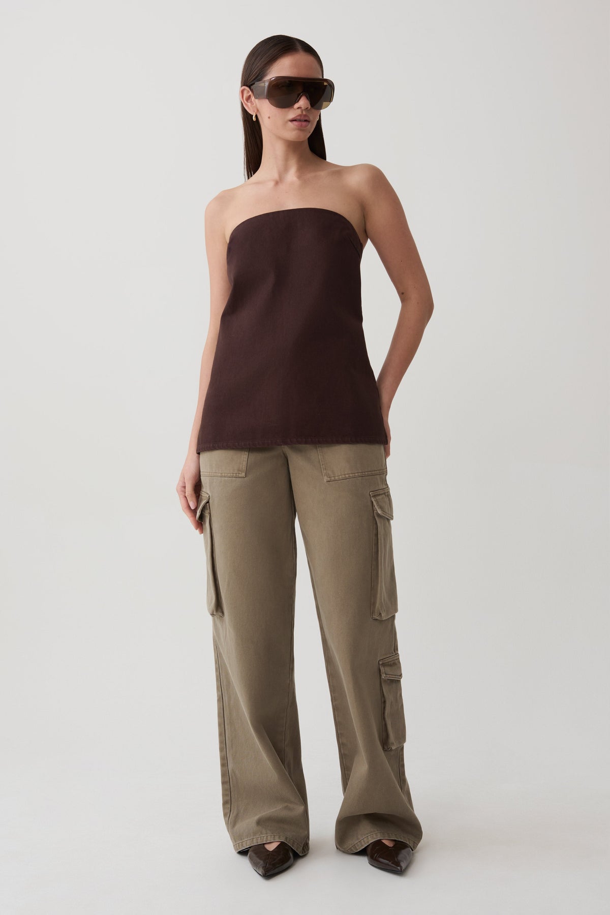 Woman wearing a strapless brown top and olive green twill denim cargo pants.