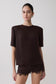 Woman wearing a dark brown shoulder pad short sleeve satin top with matching lace shorts.