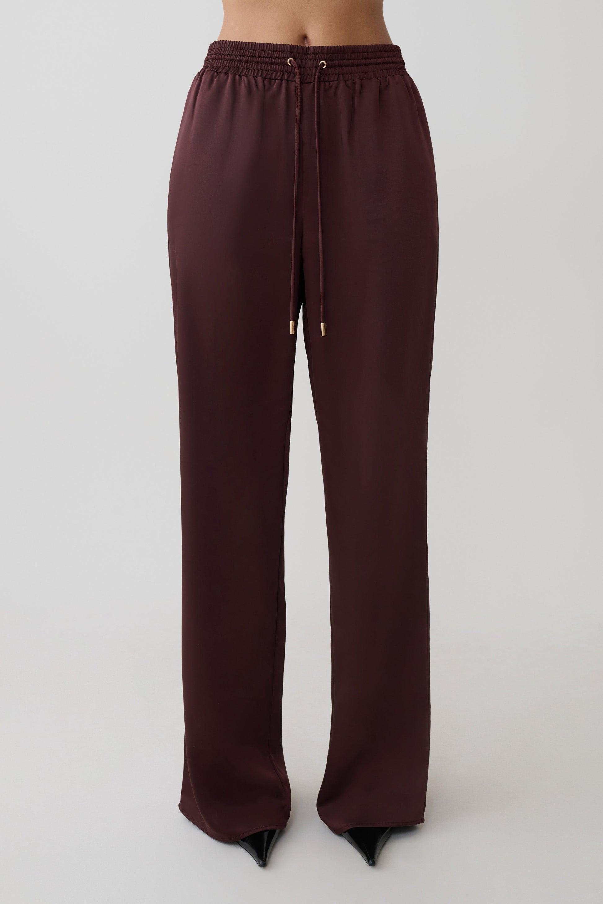 Woman wearing brown straight leg satin pants.