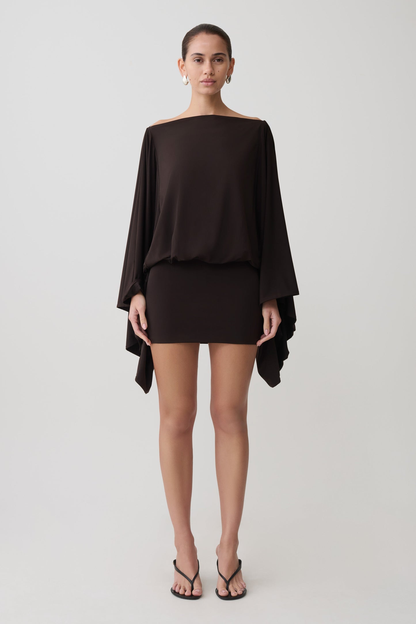 Woman wearing a dark brown draped mini dress.