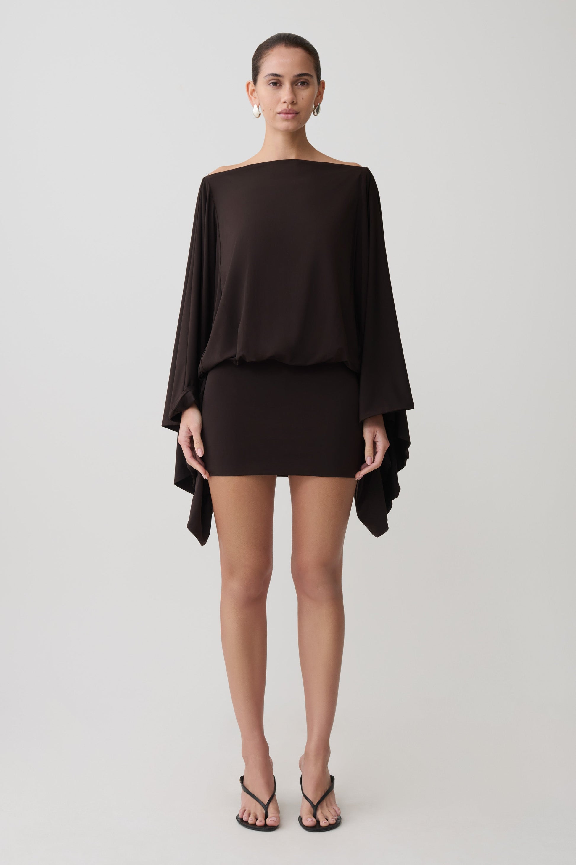 Woman wearing a dark brown draped mini dress.