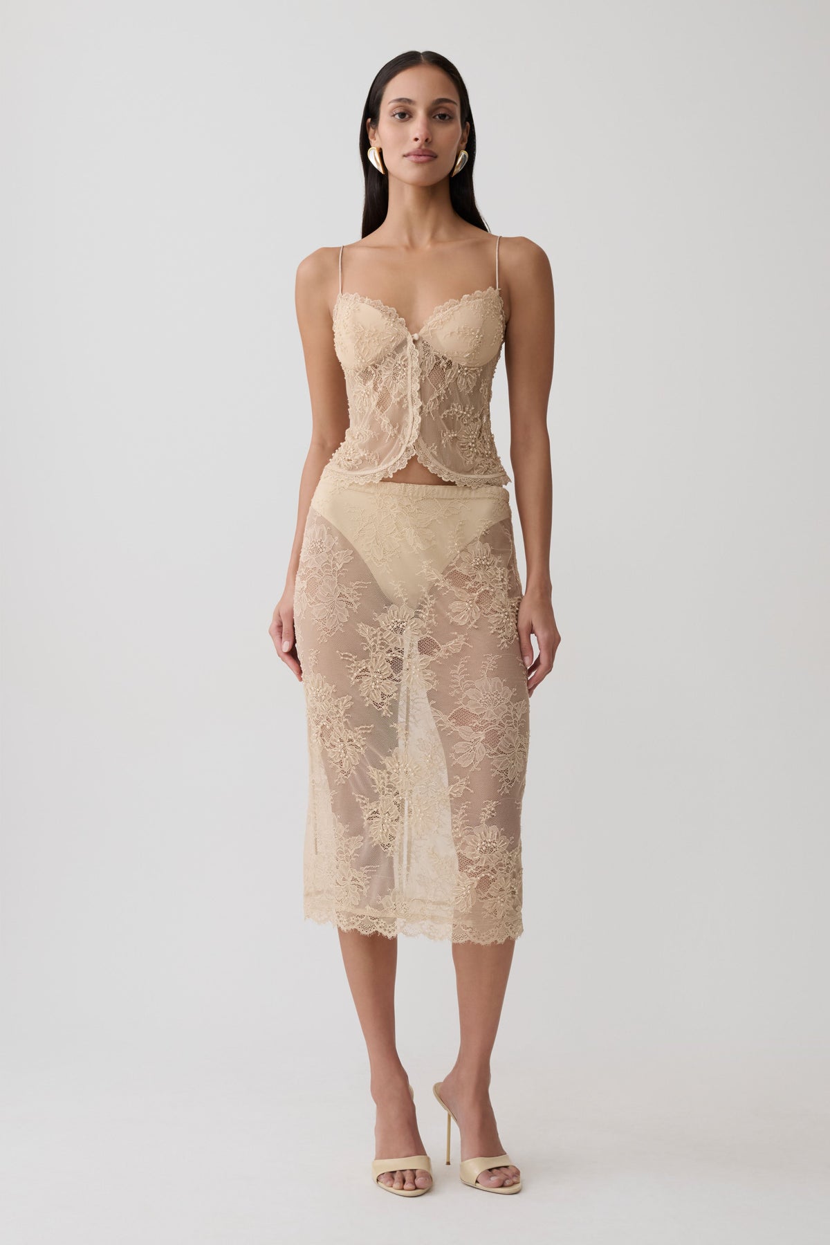 Woman wearing gold lace top with matching midi skirt.
