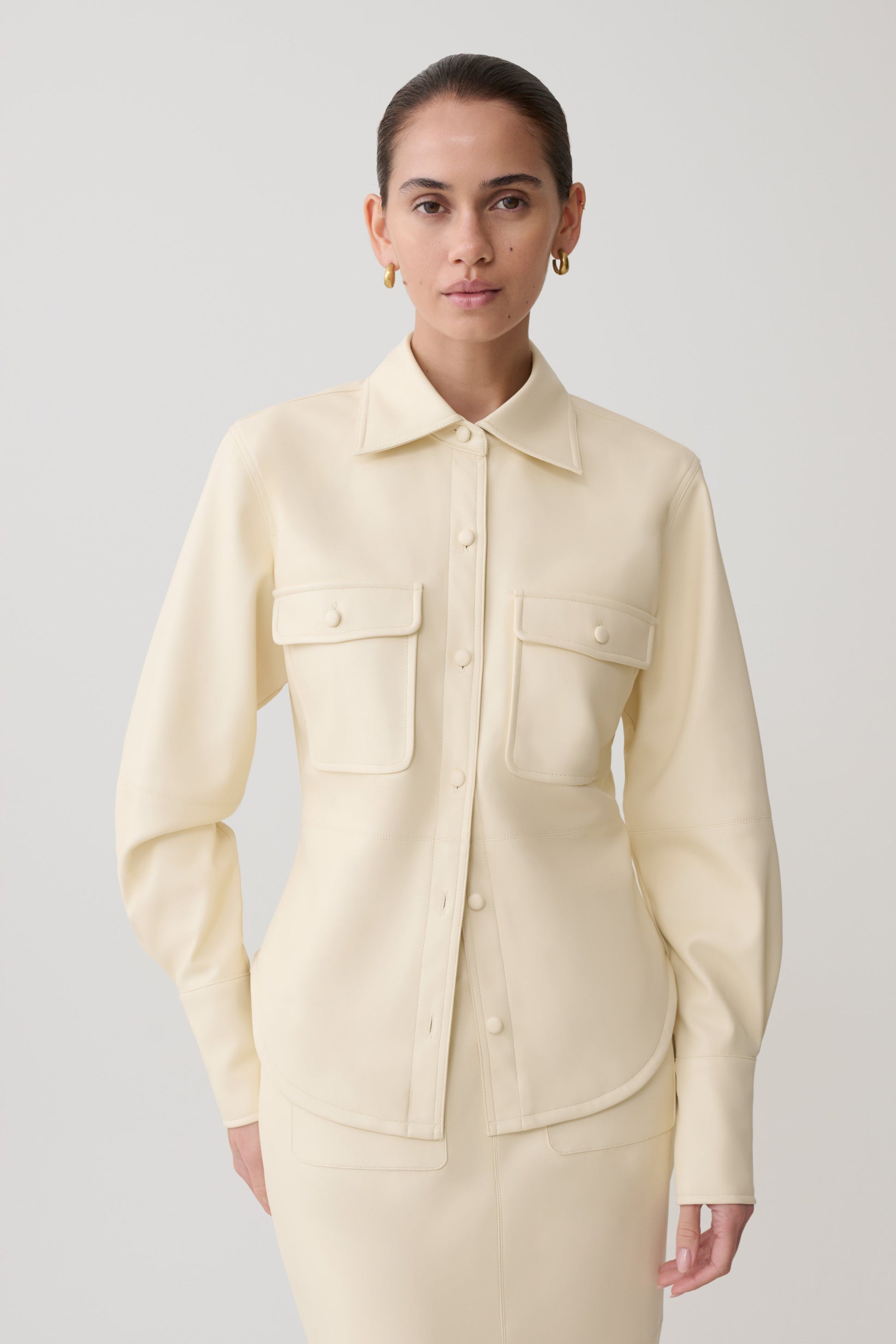 Woman wearing white faux leather shirt.