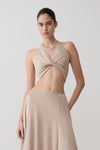 Woman wearing gold draped lurex halter top.
