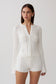 Woman wearing a white pointelle knit long sleeve top with matching shorts.