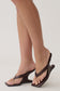 Woman wearing a dark brown curved wedge heels.