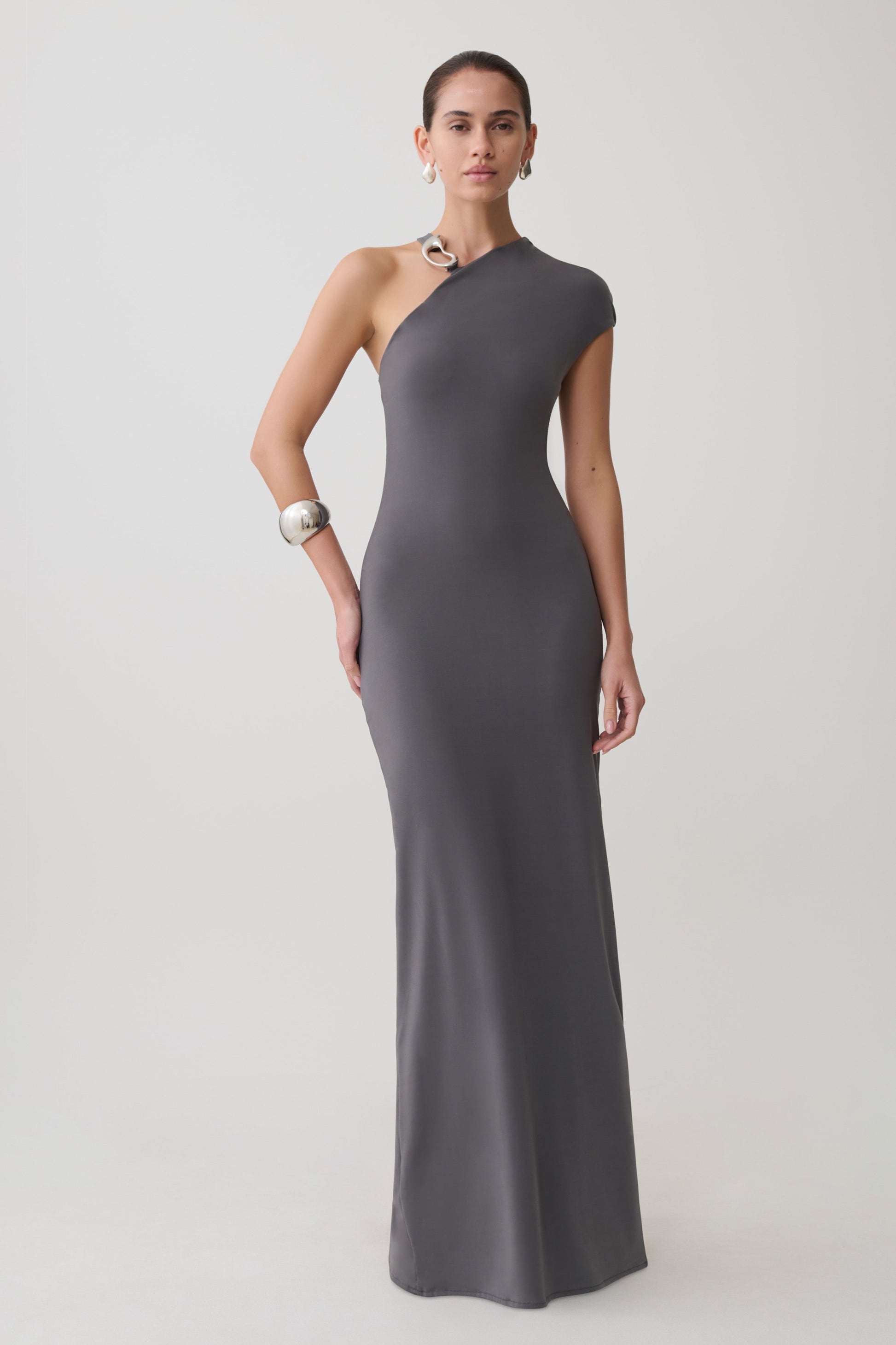 Woman wearing a grey slinky maxi dress with hardware.