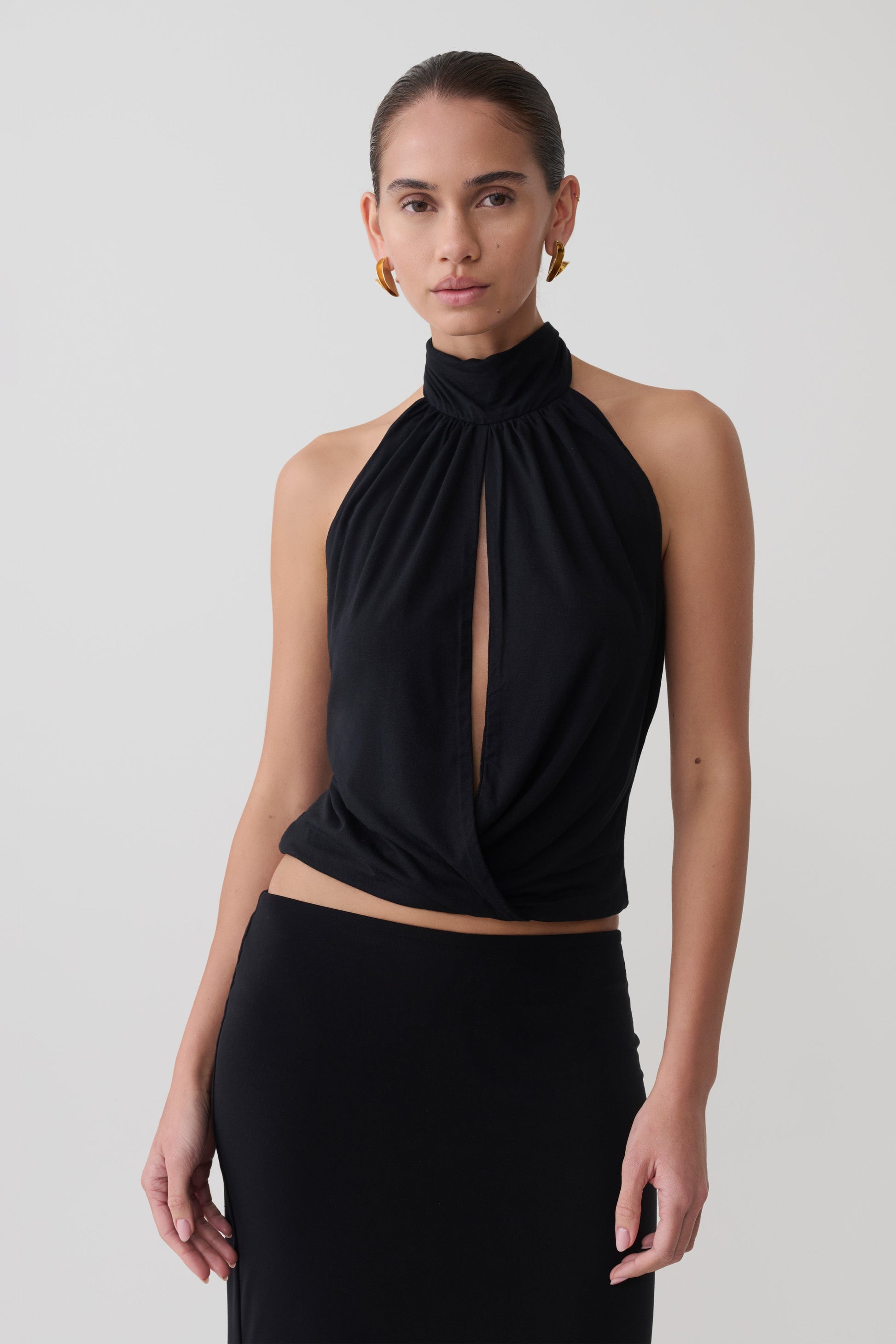Woman wearing a black sleeveless halter top.