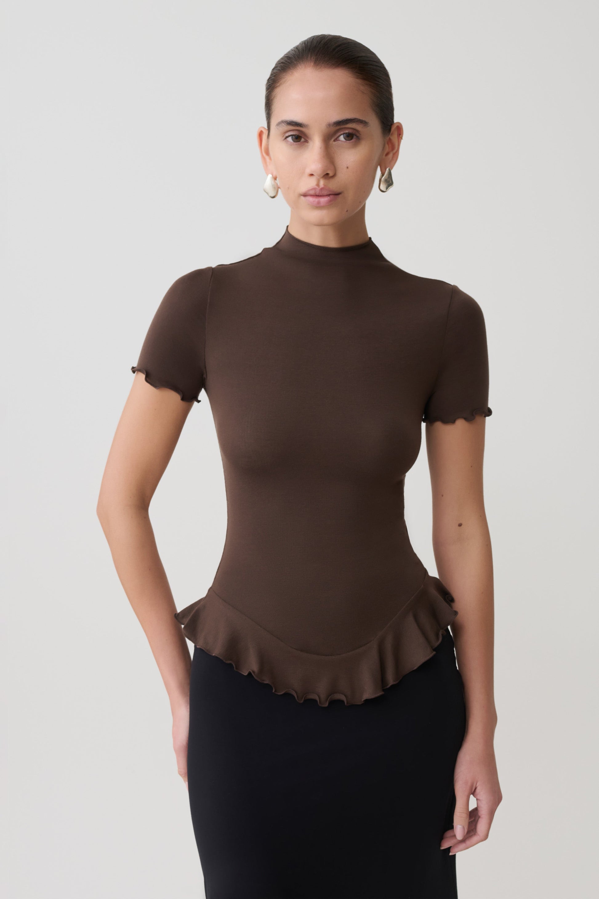 Woman wearing a brown short sleeve ruffle top.