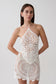 Woman wearing white crochet halter top with matching mini skirt.