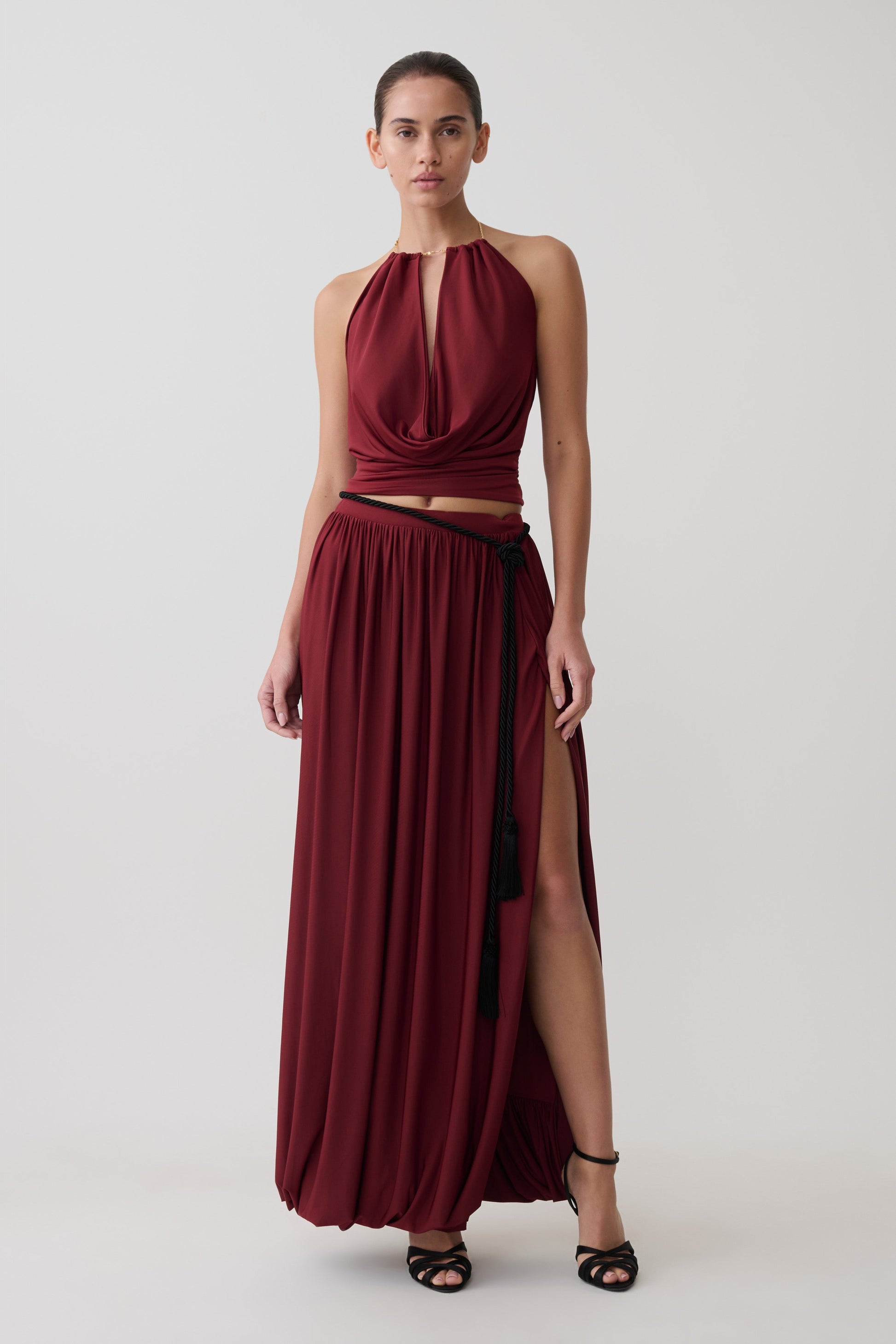 Woman wearing a dark red halter neck top  with matching bubble hem midi skirt.