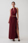 Woman wearing a dark red halter neck top  with matching bubble hem midi skirt.