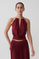 Woman wearing a dark red halter neck top with hardware.