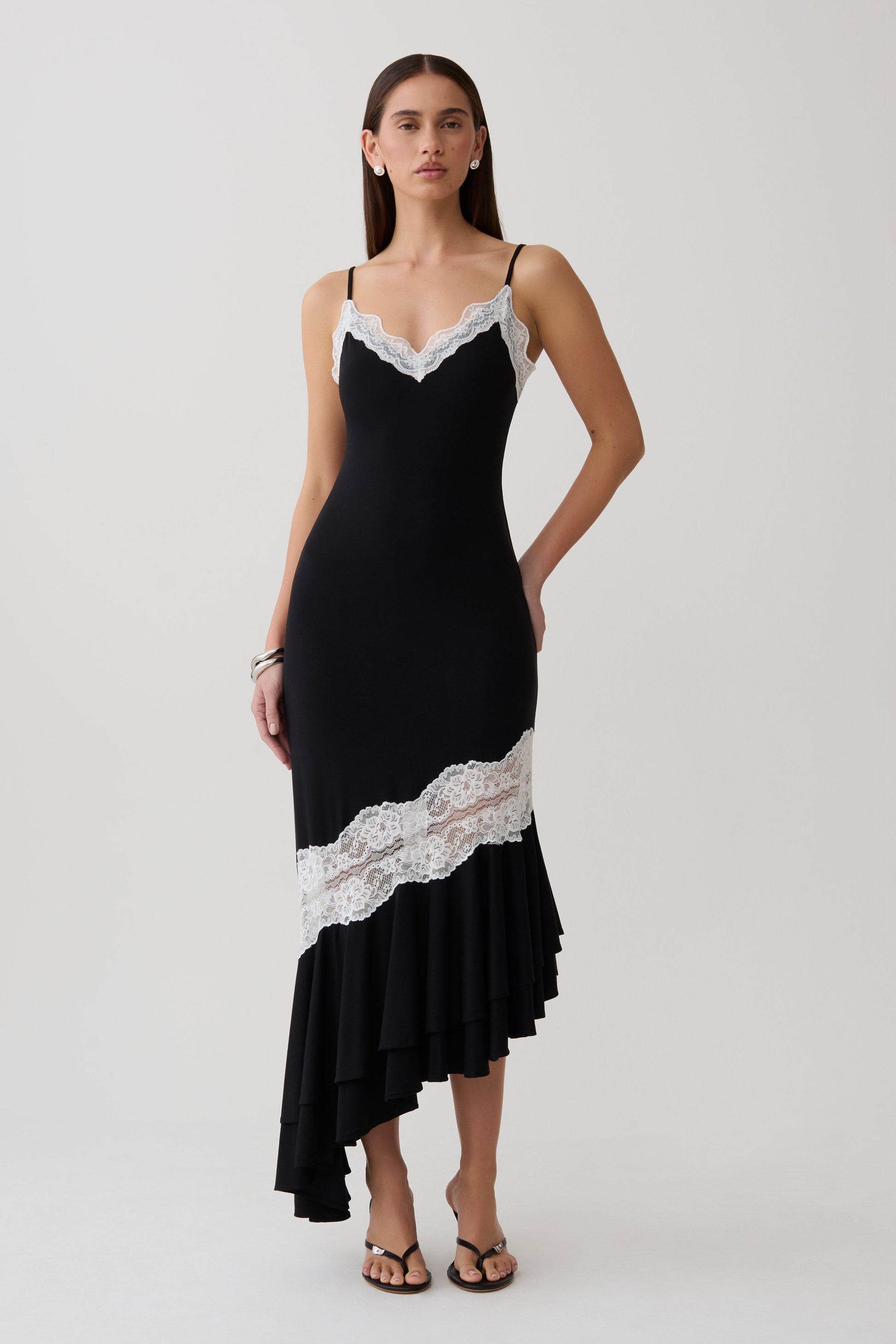 Woman wearing a black and white frilled hem lace midi dress.