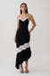 Woman wearing a black and white frilled hem lace midi dress.