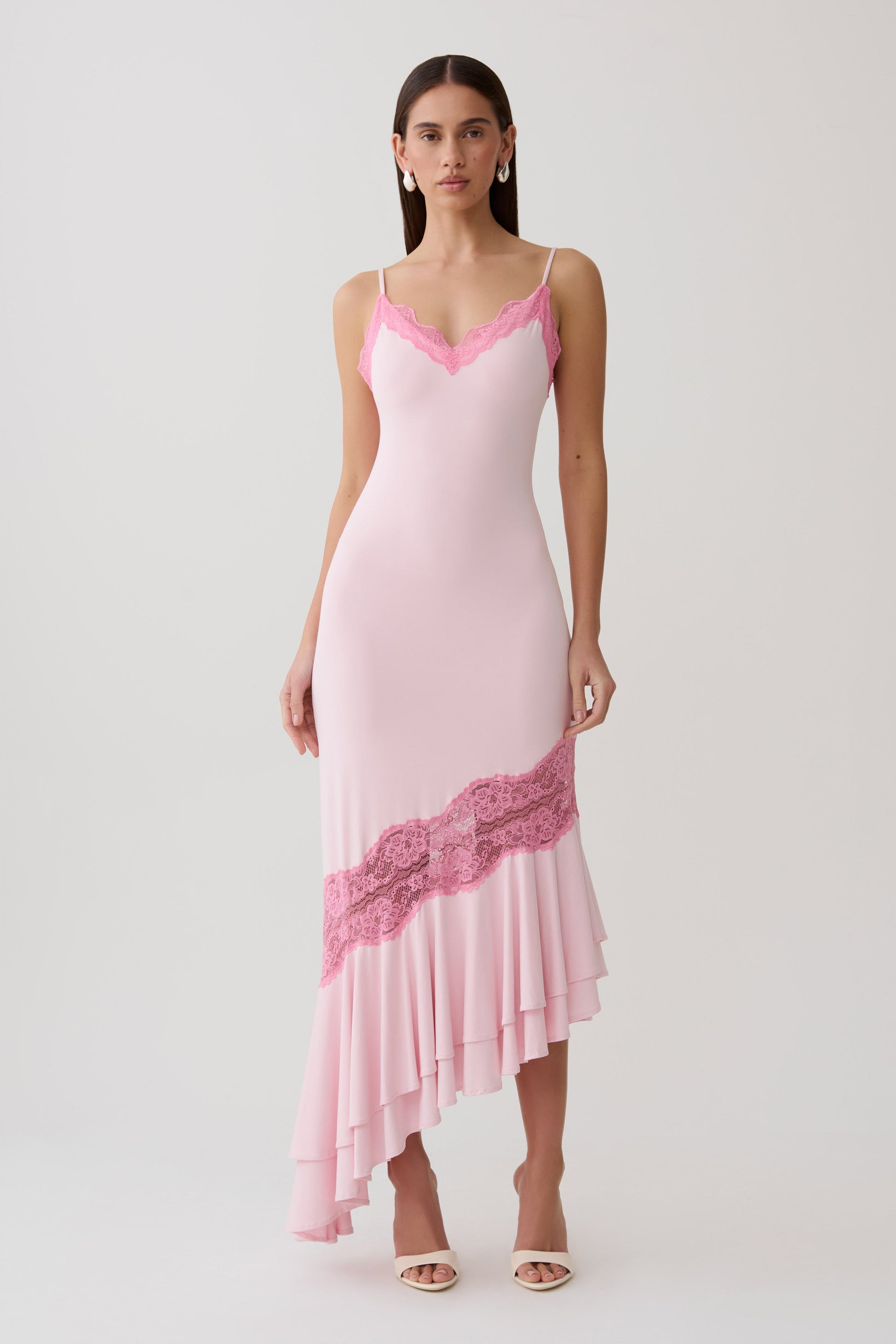 Woman wearing a pink frilled hem lace midi dress.
