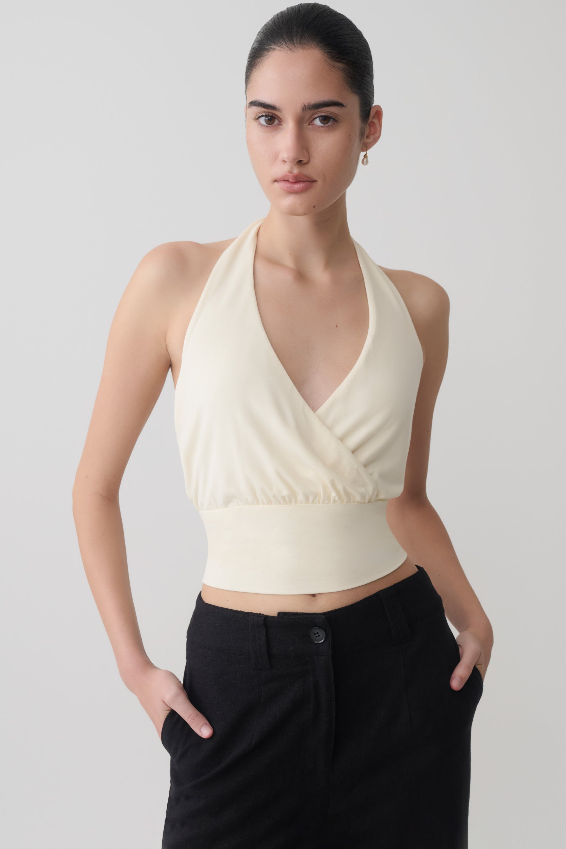 Woman wearing a white draped halter top.