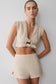 Woman wearing a beige tie front short sleeve top with matching shorts.