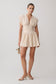 Woman wearing a beige cinched linen mini dress.