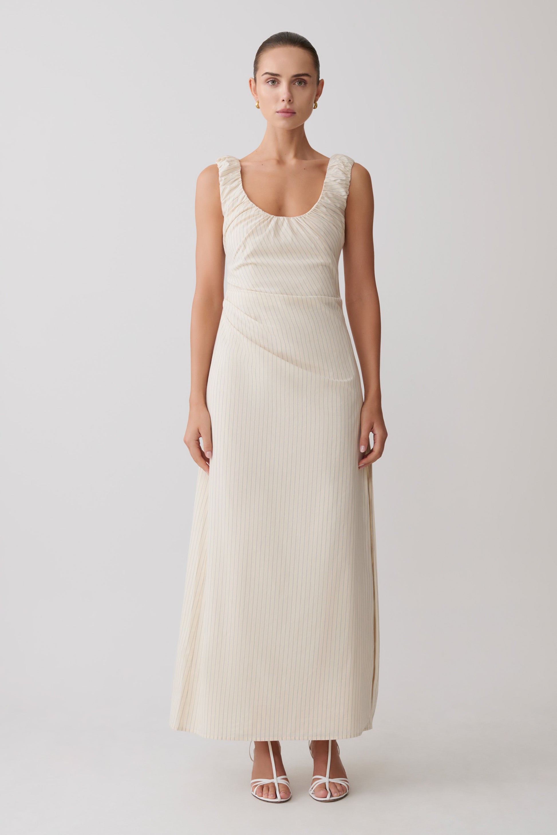 Woman wearing a cream-coloured striped maxi dress.