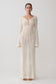 Woman wearing a long, cream-colored knitted dress against a white background