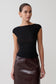 Woman wearing a black top and brown leather skirt on a white background