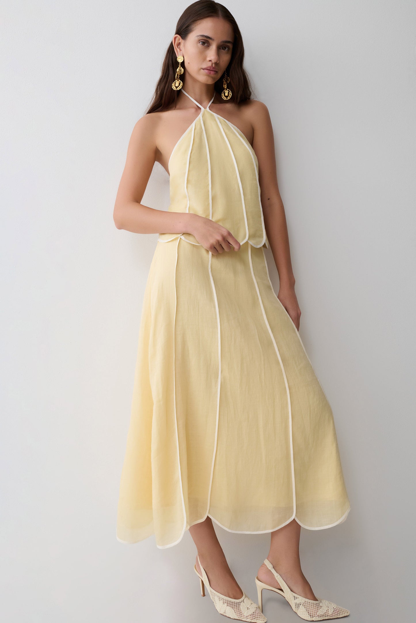 Woman wearing a light yellow panelled halter sleeveless top with matching skirt. 