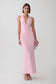A woman modeling a sleeveless, light pink bodycon maxi dress with a deep V-neckline, standing against a plain light gray studio background.