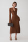 A woman models a brown ribbed long-sleeve midi dress with a button front and V-neckline, holding a black quilted handbag against a light gray studio background.