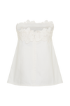 A woman modeling a strapless white top with a decorative floral lace trim across the bust, paired with wide-leg blue jeans, against a plain light gray studio background.
