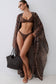 A woman models a brown two-piece bikini with a matching sheer zebra-print cover-up, holding a black woven tote bag against a plain light gray wall.